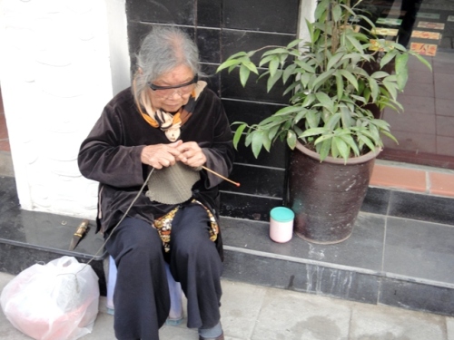 Mamie tricotant sur le trottoir