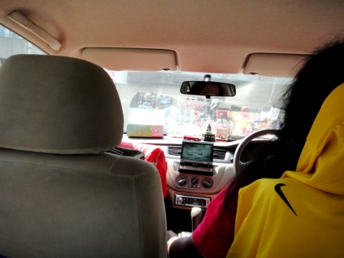 Le taximan est un homme aux cheveux à la taille, qui regarde sa télé à fond les baffles en conduisant